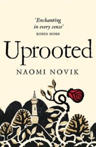 Cover for Uprooted, featuring a tower surrounded by trees and thorny bushes, with a red rose growing above them.